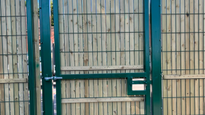A pedestrian gate in a security fence line, with privacy slats in