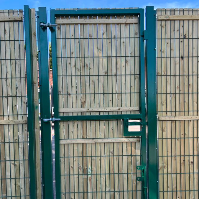 A pedestrian gate in a security fence line, with privacy slats in